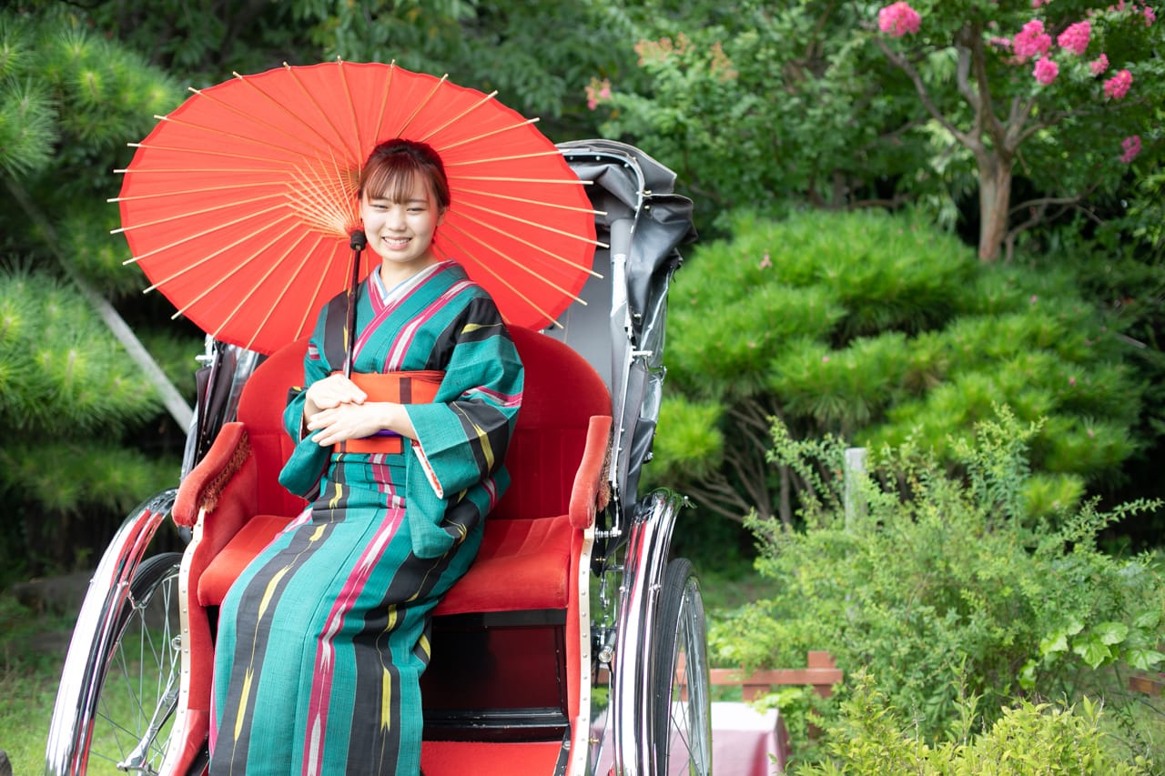 人力車に乗り和傘をさす着物の女性